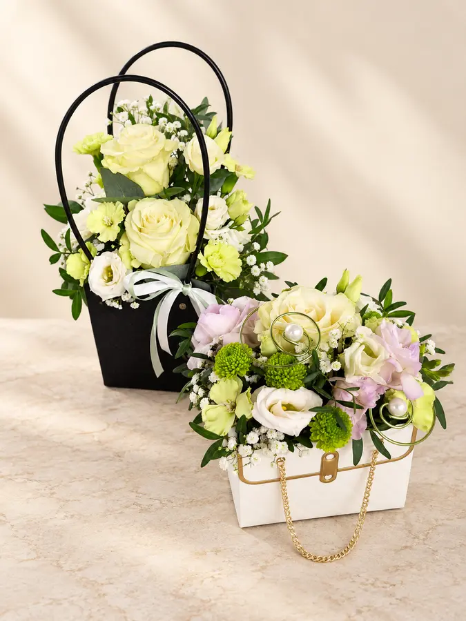 Zwei kreative Blumengestecke in schwarzen und weißen Handtaschen