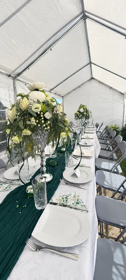 Festlich gedeckte Hochzeitstafel mit hohen Blumengestecken in Weiß und Grün