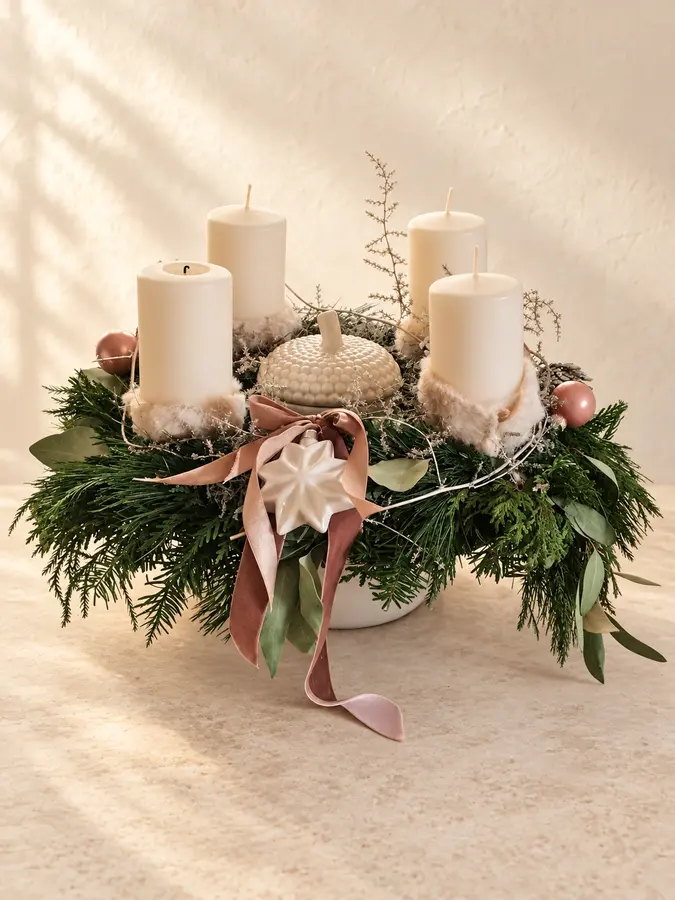 Adventsgesteck mit vier cremefarbenen Kerzen, Tannengrün und roséfarbenen Akzenten