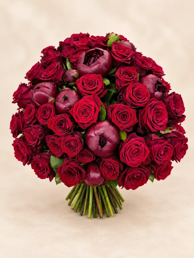 Runder Blumenstrauß aus dunkelroten Rosen und Pfingstrosen