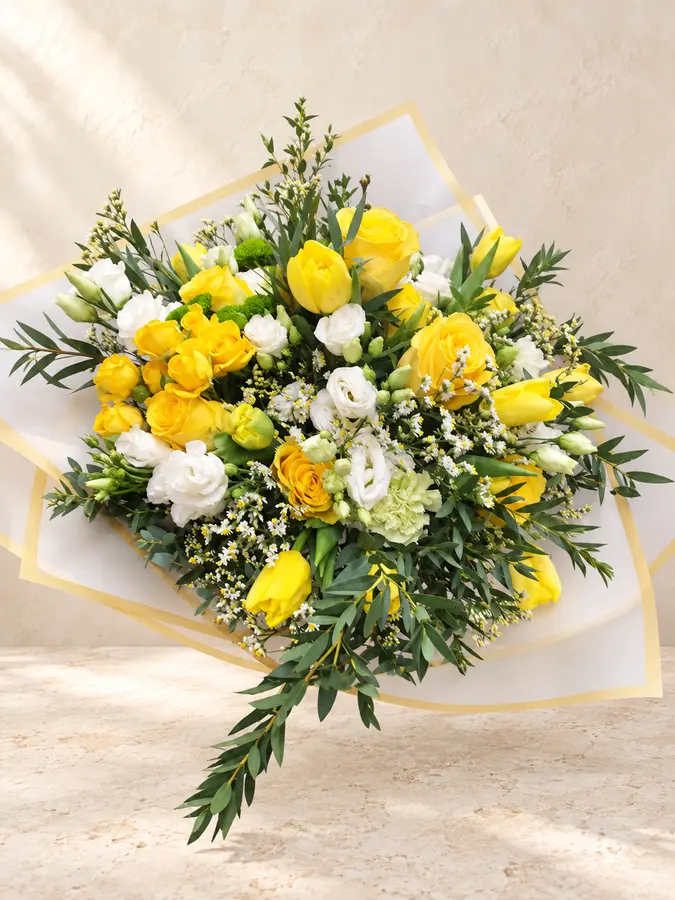Frischer Blumenstrauß mit gelben Rosen und Tulpen sowie weißen Blüten