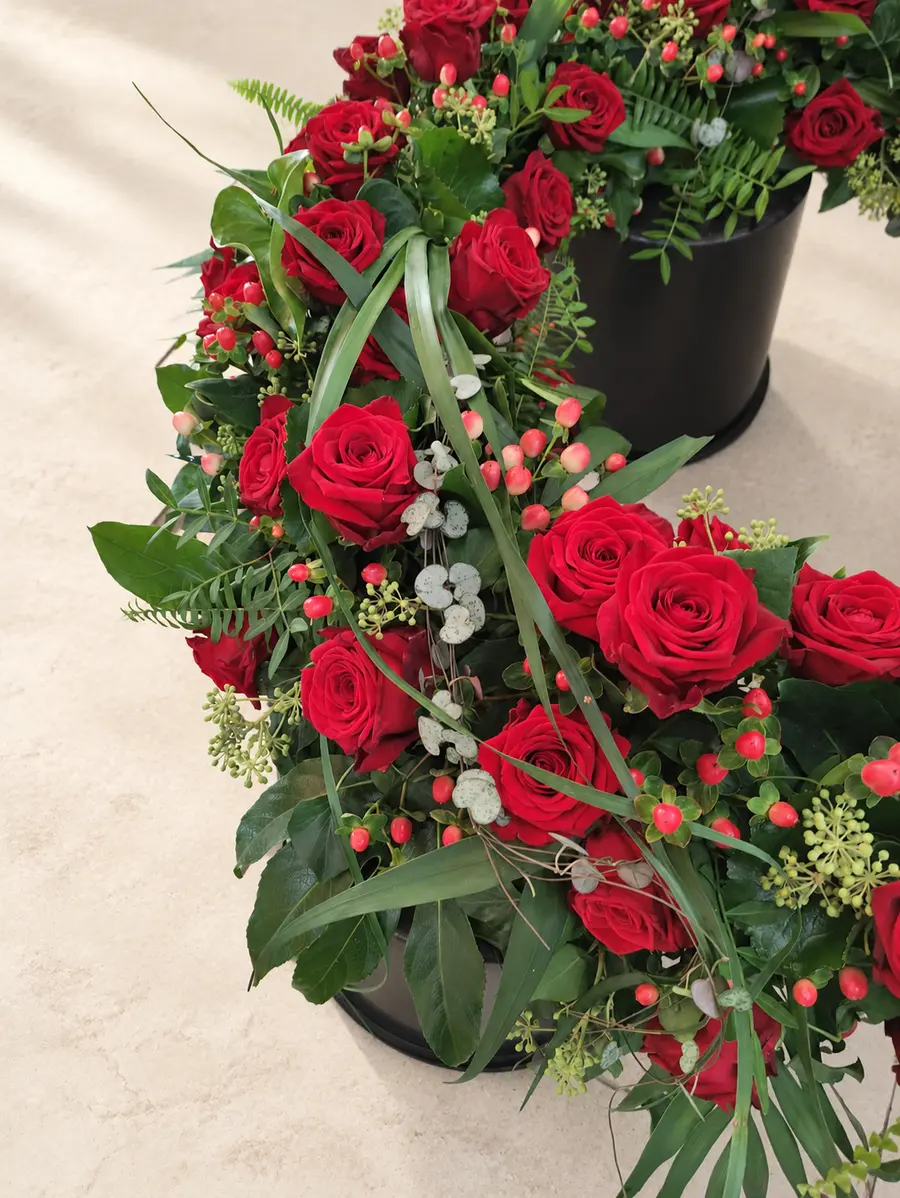 Detail eines Trauerkranzes aus roten Rosen und Grün